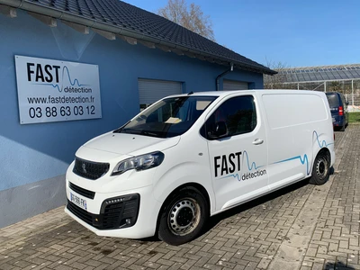Scène extérieure dans un parc avec personnel en uniformes inspectant un véhicule militaire blindé