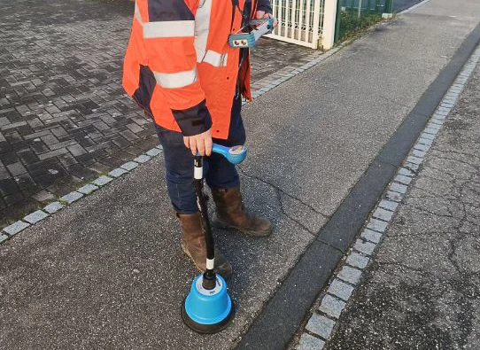 Scène extérieure sur asphalte avec intervention technique sur canalisation