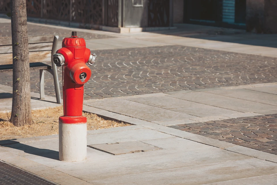 Artisan en chemise à carreaux tenant un multimètre numérique jaune, portant une ceinture à outils professionnelle grise et orange équipée de tournevis, pinces et instruments de mesure électrique